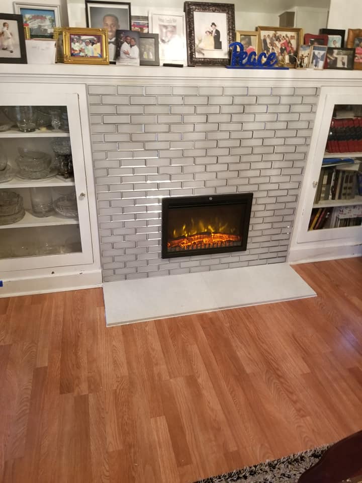 Completed fireplace renovation with fresh tile and built-in shelving.