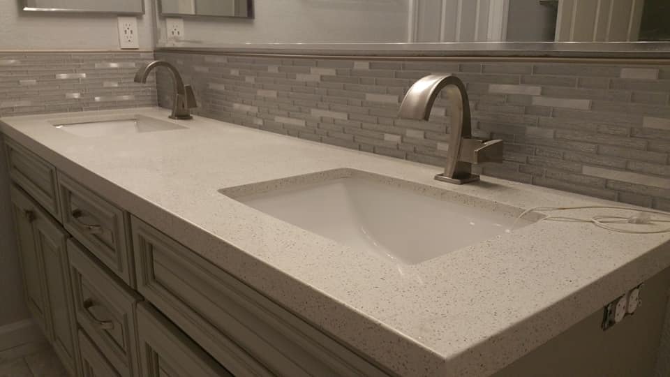 Finished double-sink vanity with countertop, backsplash, and installed fixtures.